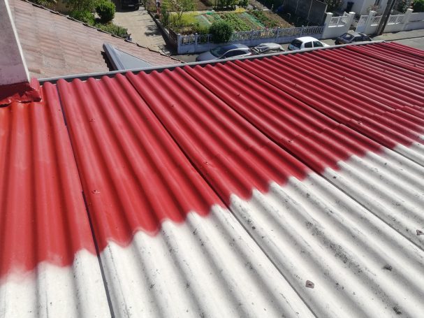 Toit ondulé avec des bandes rouges et blanches, angle supérieur, vue sur le jardin en bas.